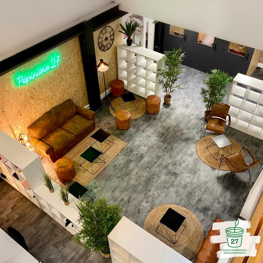 L'espace commun de la Pépinière 27 vu d'en haut : canapé de cuir, tables basses, plantes et l'enseigne au néon « Pépinière 27 ».